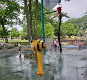 Spray feature decorated to look like bumblebee and large water dumping feature at splashpad inside Capron Park Zoo in Attleboro MA.