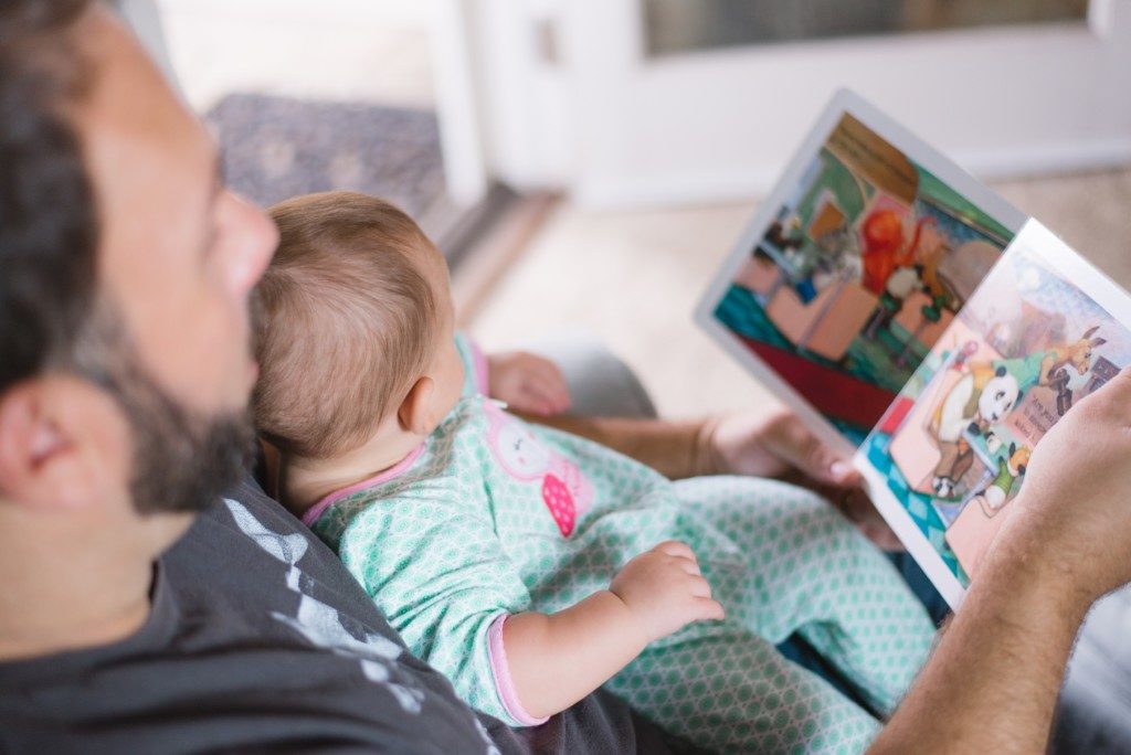 father reading to infant daughter Providence Moms Blog