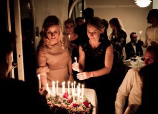 Two women standing by a birthday cake with lit candles. Image in Providence Moms Blog post on life lessons