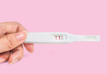 hand holding a positive pregnancy test stick, fertility