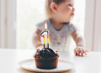 baby with cupcake and candle in the shape of a number one