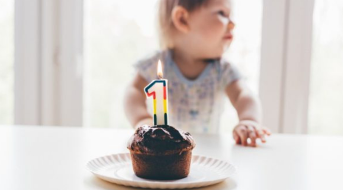 baby with cupcake and candle in the shape of a number one