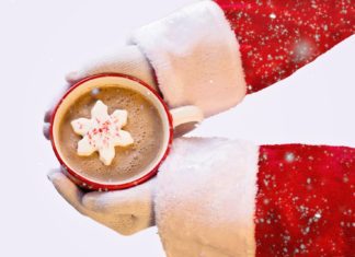 santa hands holding mug of hot chocolate with snowflake inside