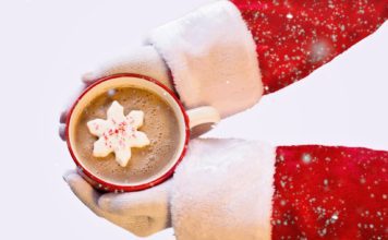 santa hands holding mug of hot chocolate with snowflake inside