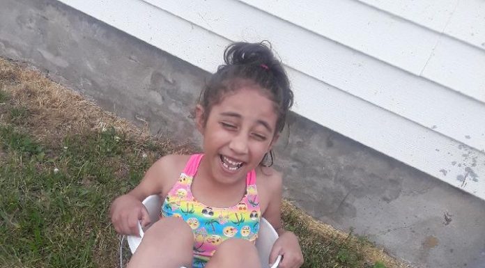 brown child smiling wearing bathing suit in bucket