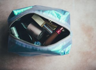 a shiny make up bag with an open zipper showing a jumble of make up inside