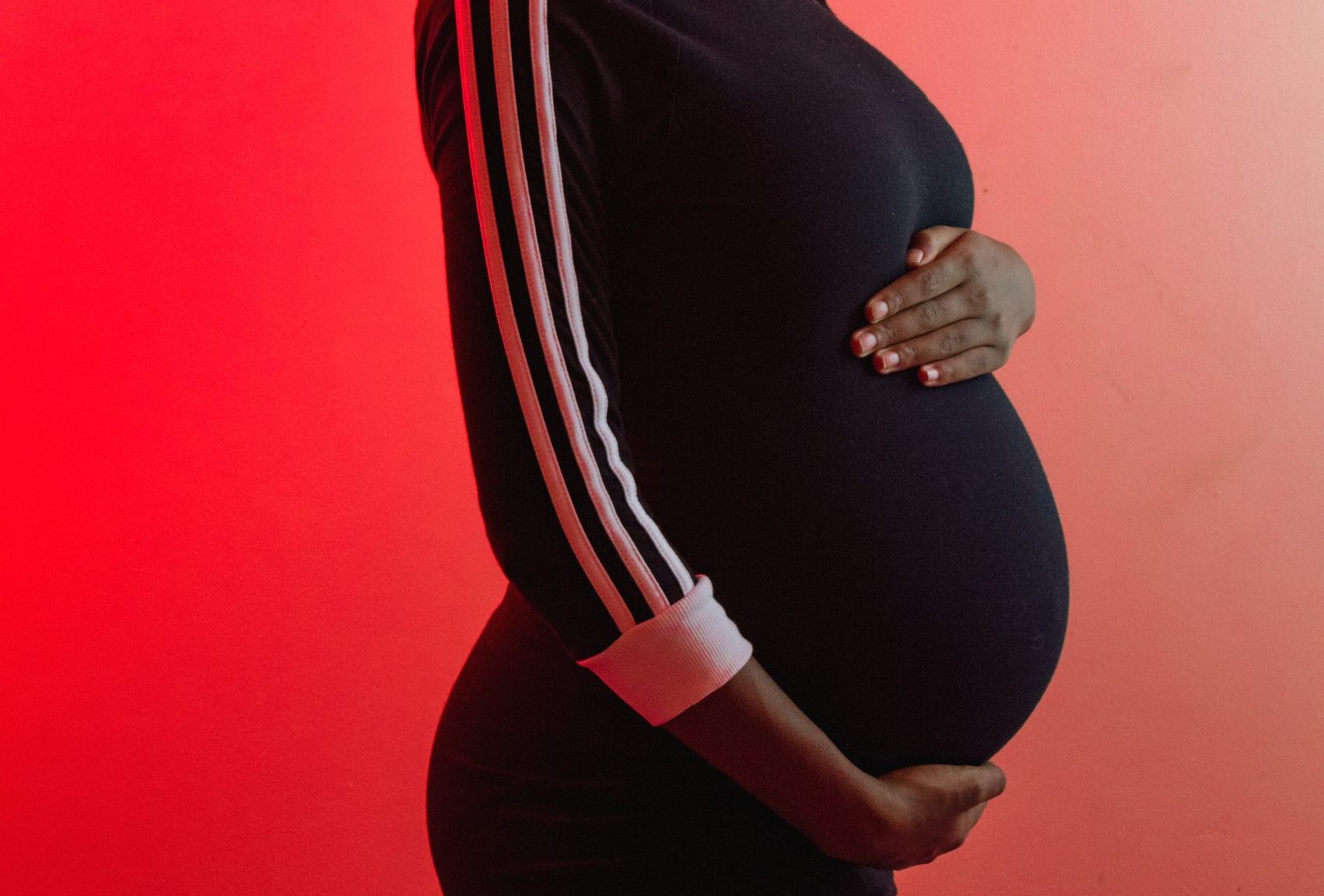 pregnant belly wearing black shirt held by dark brown hands